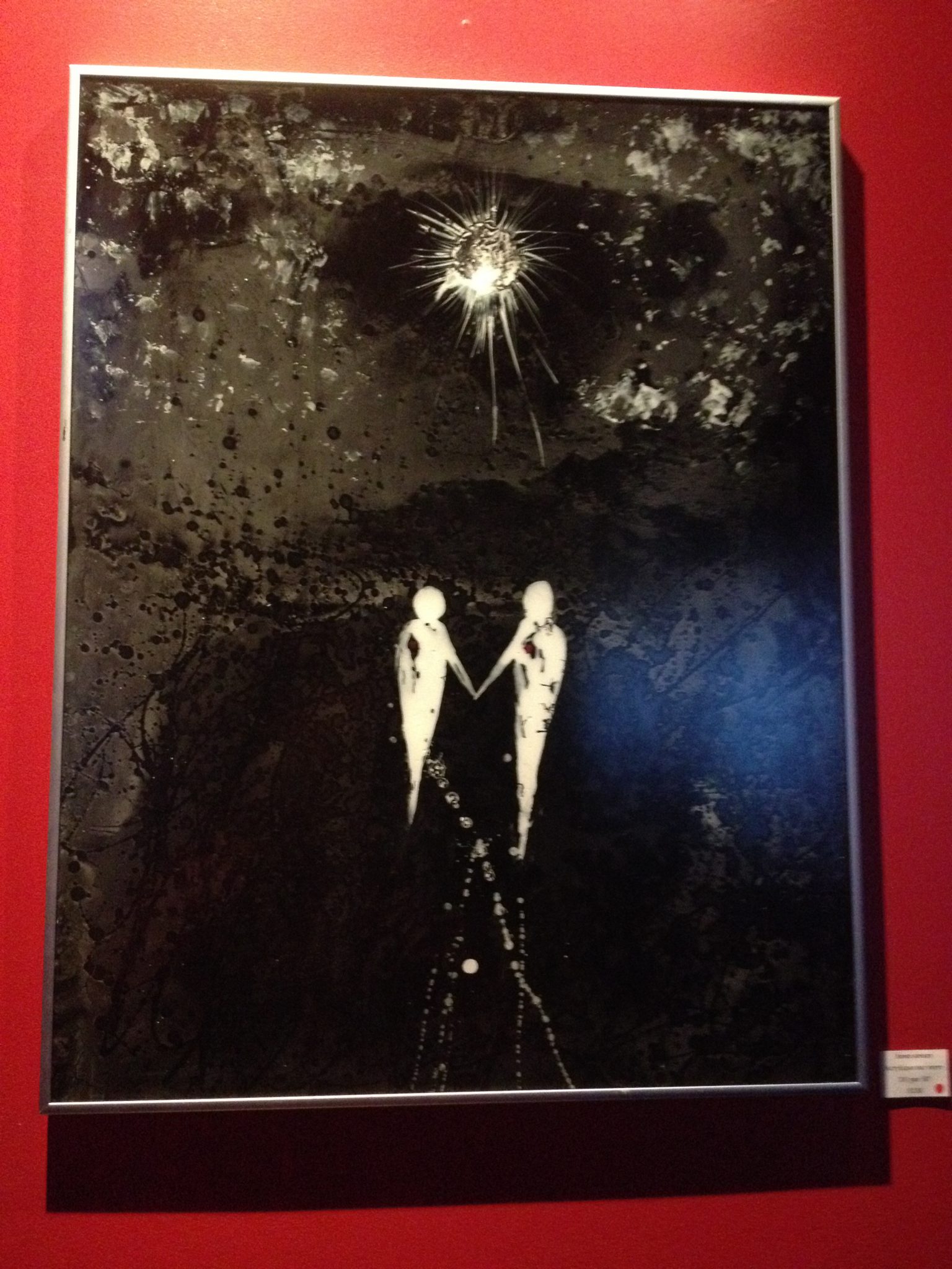 La toile monochrome Âmes sœurs présente des personnages rudimentaires qui flottent sous une lune radieuse. Photo: M.-C. Perras
